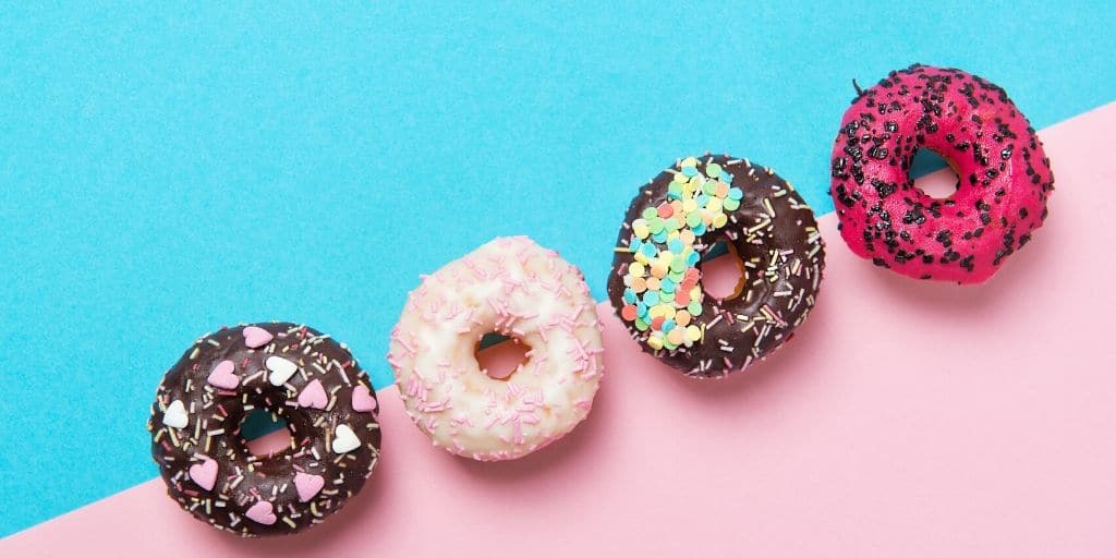 Blue and pink background with donuts lined up in a diagonal. 